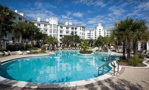 A large pool surrounded by lounge chairs and palm trees, with a white building in the background. - Opulent Couples Retreat In Sandestin's Baytowne wharf (Miramar Beach)