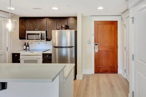 Una cocina moderna con electrodomésticos de acero inoxidable, una puerta de madera y una encimera blanca.
