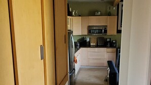 Corredor que dá para uma cozinha com armários e micro-ondas.