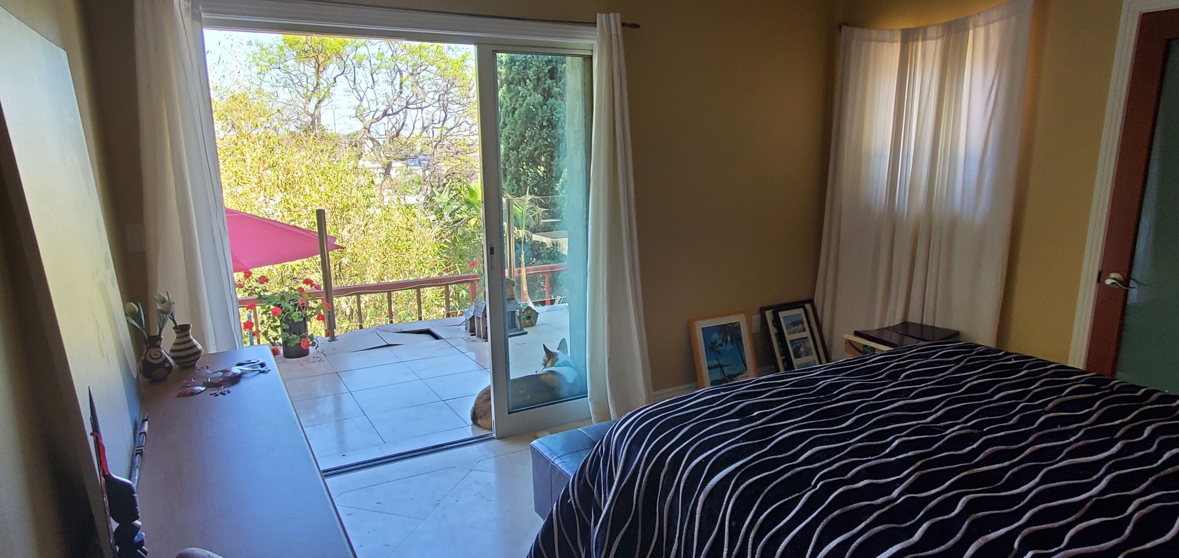Un dormitorio con una cama, un ventanal corredero que da a un balcón y vistas a zonas verdes.