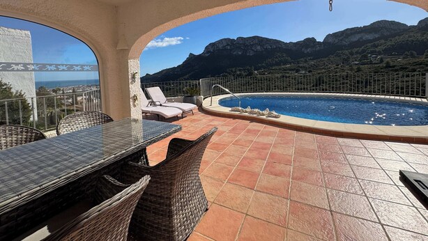 A rooftop terrace with a swimming pool, lounge chairs, and a view of mountains.