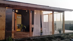 A wooden building with the name 'RIO OCULTO' on the side, a wooden deck, and a view of the landscape.