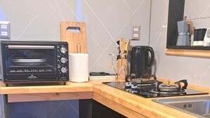 A kitchen with a built-in toaster oven, a wooden cutting board, a coffee maker, and a sink.