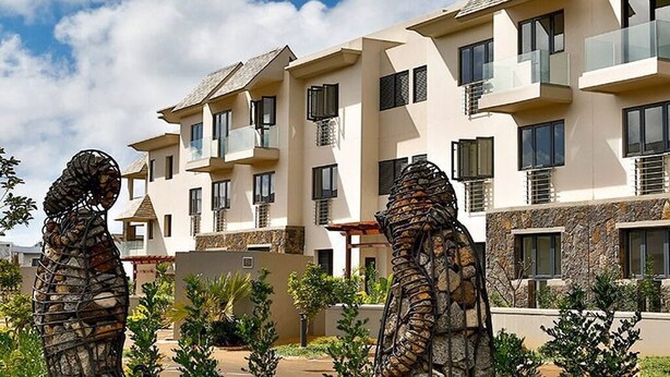 A multi-story hotel with balconies, a stone facade, and a clear sky. - Luxury apartment in Azuri, Mauritius (Rivière du Rempart)