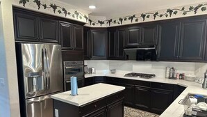 A kitchen with dark cabinets, stainless steel appliances, and a white countertop. - 生日和结婚与节日派对
Birthday, Wedding, and Holiday Parties (Rancho Cucamonga)