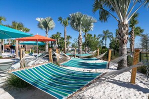 Un complexe hôtelier en bord de mer, doté de hamacs, de parasols et de palmiers.