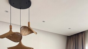 A modern dining area with a round table, wicker chairs, and a flat-screen TV in the background. - Aqua Esmeralda • Luxury Beachfront • Curazao 103 (Dominicus)