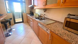 Cocina con armarios de madera, encimera de granito, horno empotrado y una ventana con persianas.