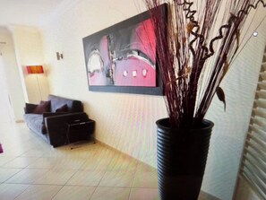 Ein Wohnzimmer mit einer Couch, einem Couchtisch, einer Topfpflanze und einem Gemälde an der Wand.