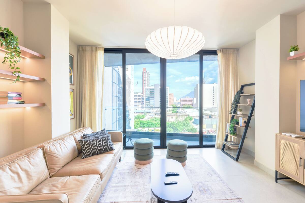 Una sala de estar moderna con un sofá, otomanas, una mesa de centro y un mueble para la televisión.