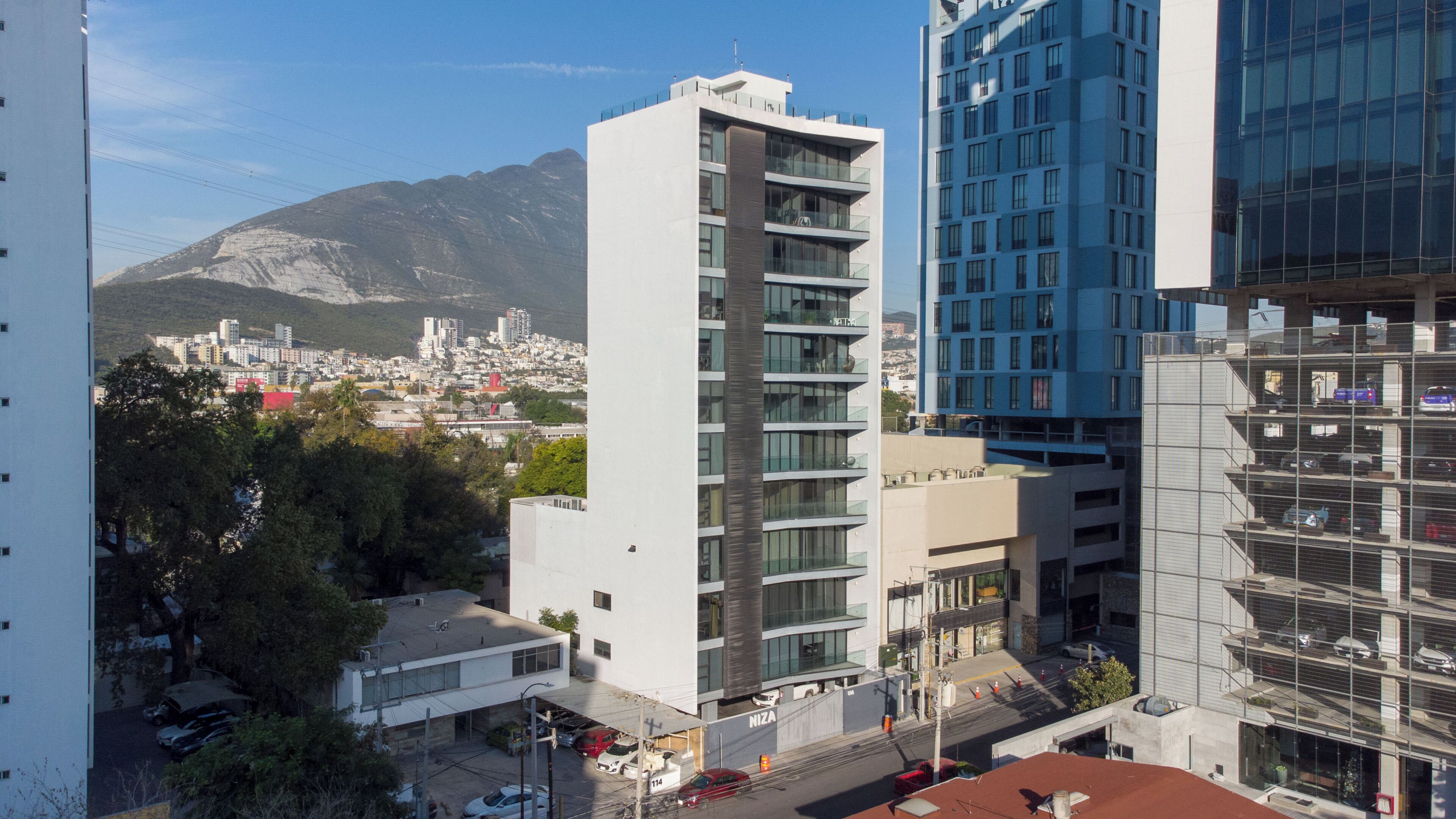 Un edificio de varios pisos con un diseño arquitectónico moderno, que destaca por un elemento vertical prominente y un fachada de vidrio.