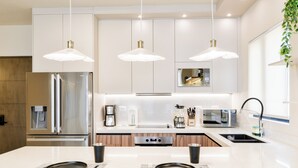 A modern kitchen with stainless steel appliances, pendant lighting, and a central island with seating. - Niza (Monterrey)