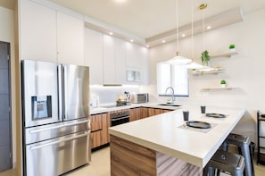 A modern kitchen with stainless steel appliances, wooden cabinets, and a central island. - Niza (Monterrey)
