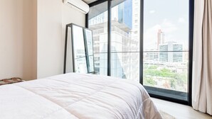 A bedroom with a large window, a bed, and a mirror. - Niza (Monterrey)