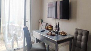 A dining area with a table, chairs, a TV, and a view through a glass door. - Casa della Mamma by Interhome (Sanremo)