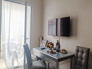 Ein Essbereich mit Tisch, Stühlen, einem Fernseher und Blick durch eine Glastür.
