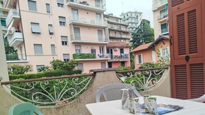 A balcony with a table and chairs, overlooking a residential area with multi-story buildings. - Casa della Mamma by Interhome (Sanremo)