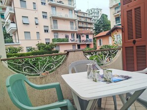Ein Balkon mit Tisch und Stühlen, mit Blick auf ein Wohngebiet mit mehrstöckigen Gebäuden.