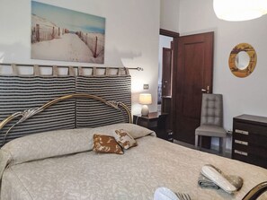 Ein Hotelzimmer mit Bett, Sessel, Schreibtisch und einem Gemälde an der Wand.