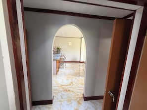 An interior hallway with a marble floor, an archway, and a dining area in the background.
