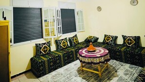 A living room with a patterned rug, a central ottoman, and a chandelier. - Amazigh host Taroudannt (Taroudant)