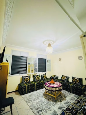 A living room with a sofa set, a coffee table, a lamp, and a window with shutters.