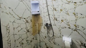 A bathroom with marble-patterned walls, a handheld showerhead, a soap dispenser, and a toilet paper holder. - Amazigh host Taroudannt (Taroudant)