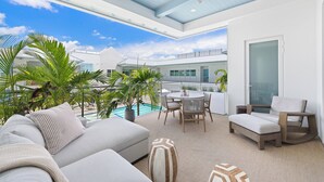 A modern outdoor living area with a pool, lounge chairs, and a dining table. - Olde Naples Gem | Beach, Dining & Resort Style Living (Naples)