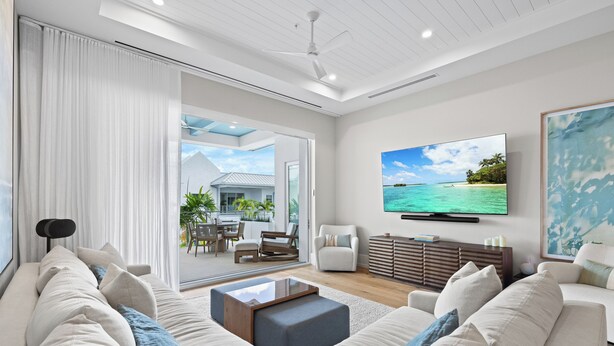 A modern living room with a large TV, comfortable seating, and a view of the outdoors. - Olde Naples Gem | Beach, Dining & Resort Style Living (Naples)