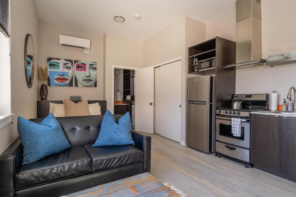 A compact living space with a kitchenette, a sofa with blue cushions, and a dining area.