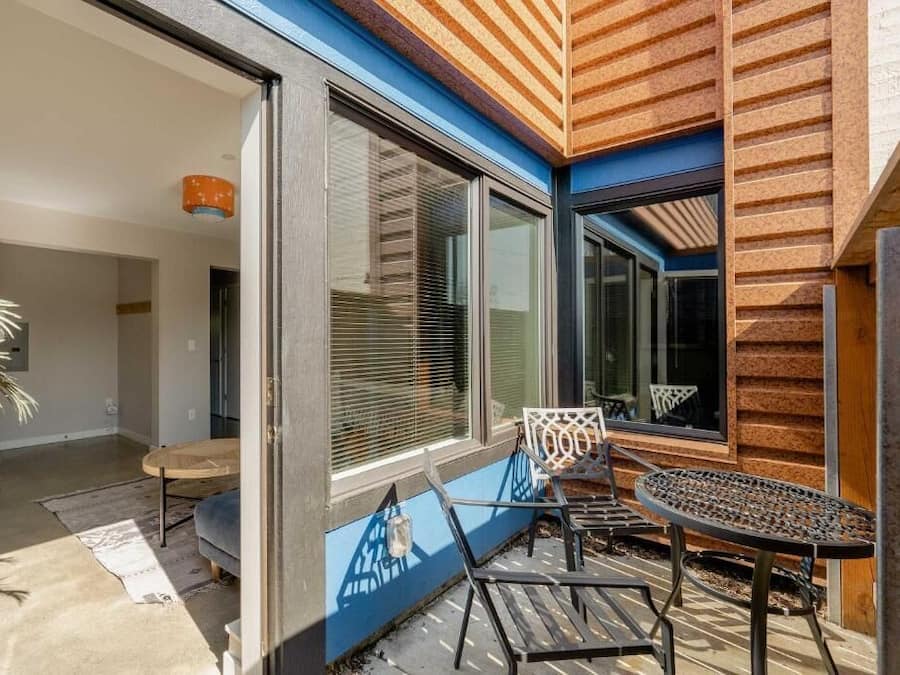 A modern room with large windows, a sliding door, and a small seating area with a table and chairs.