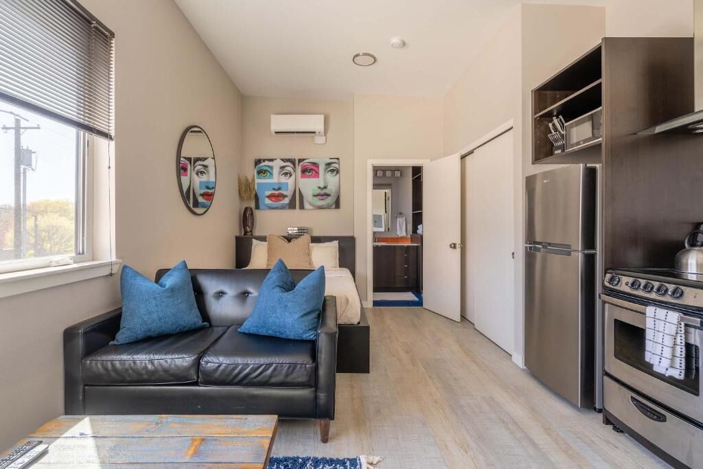 A modern apartment with a living area, a kitchenette, and a bedroom.