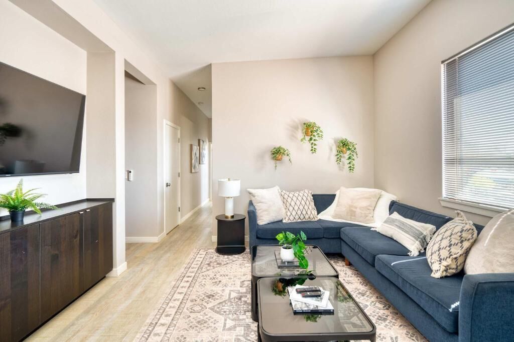 A modern living room with a dark sofa, a coffee table, and a TV mounted on the wall.