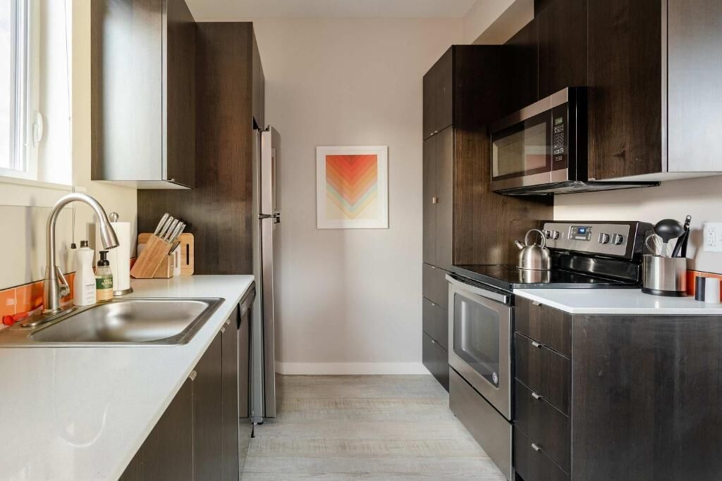 Cozinha moderna com armários de madeira escura, eletrodomésticos de aço inoxidável e design minimalista.