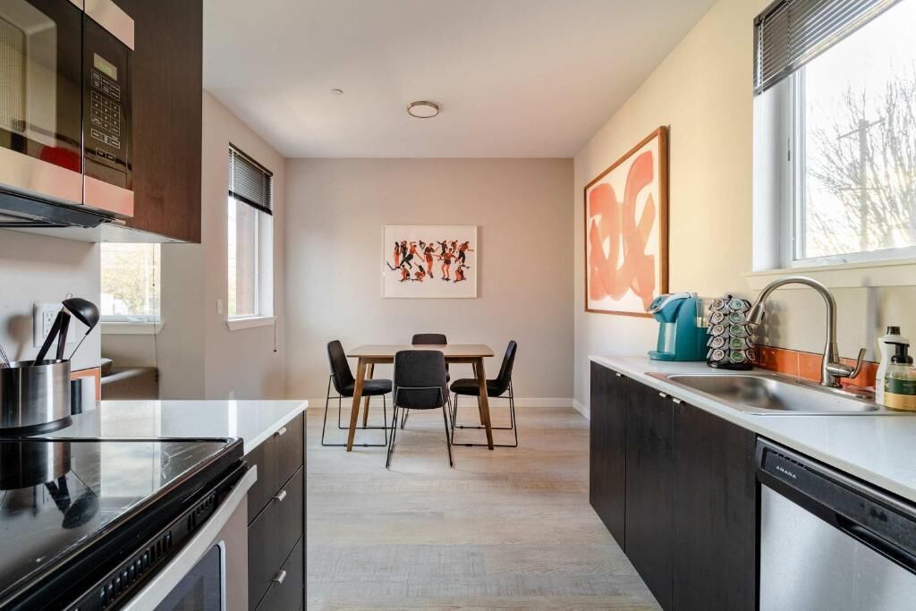 Une cuisine moderne avec un coin repas, comprenant une cuisinière, un évier et une table avec des chaises.