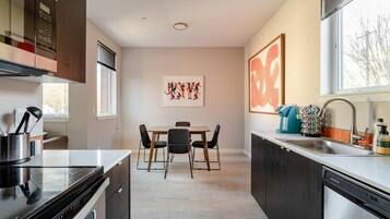 Une cuisine moderne avec un coin repas, comprenant une cuisinière, un évier et une table avec des chaises.