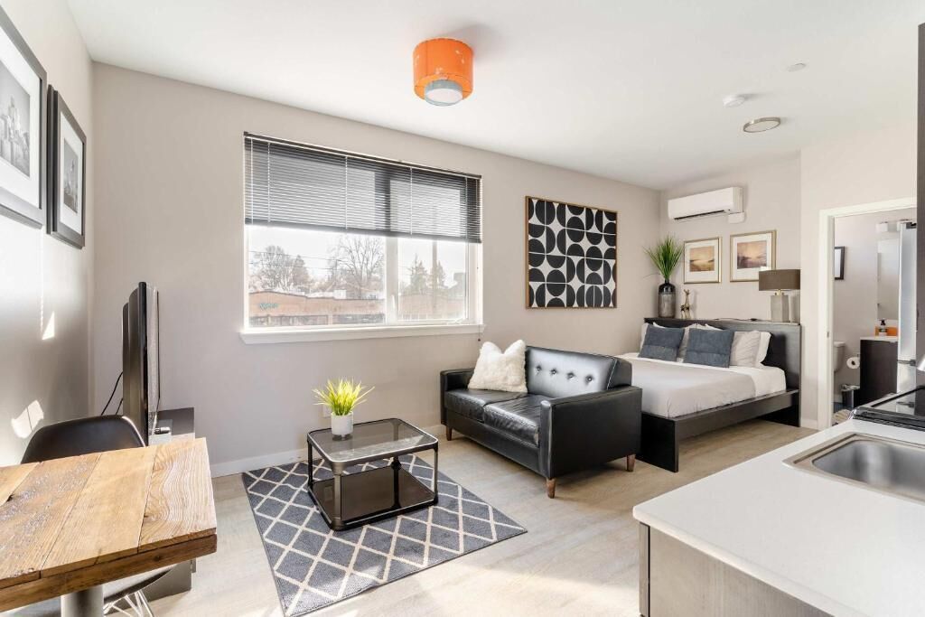A modern living room with a sofa, a bed, a coffee table, and a TV.