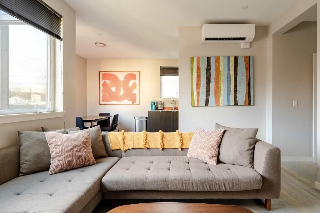 Una sala de estar con un sofá modular, una mesa de centro, un comedor con mesa y sillas, y obras de arte en las paredes.