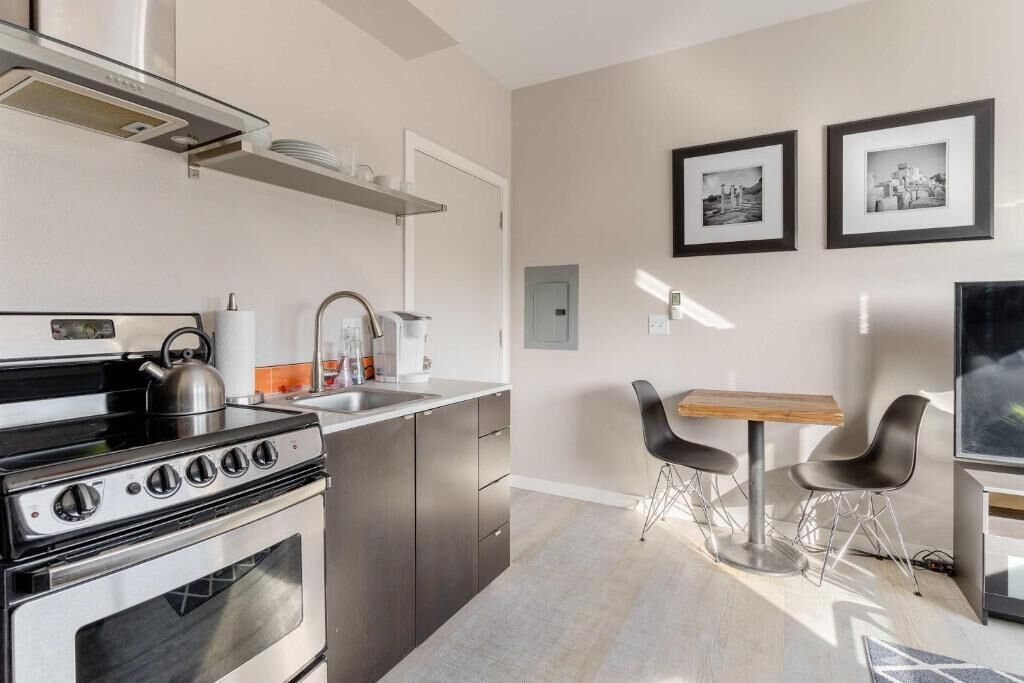 A modern kitchen with a stove, sink, and dining area with chairs.