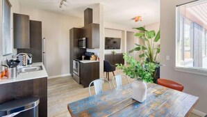 Una cocina moderna con armarios oscuros, una mesa de comedor con sillas y una planta grande en maceta.