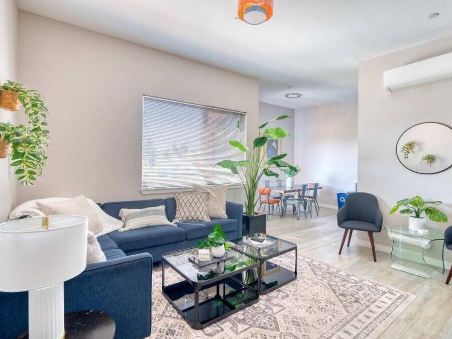 En moderne stue med sofa, sofabord og potteplanter.