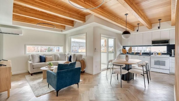 Een modern interieur met een houten plafond, een eethoek, een keuken en een zithoek met een bank en stoelen.