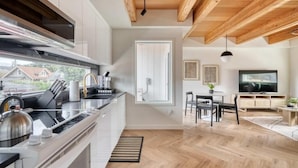 Een moderne keuken met een groot eiland, een eethoek met tafel en stoelen, en een televisie in de woonkamer.