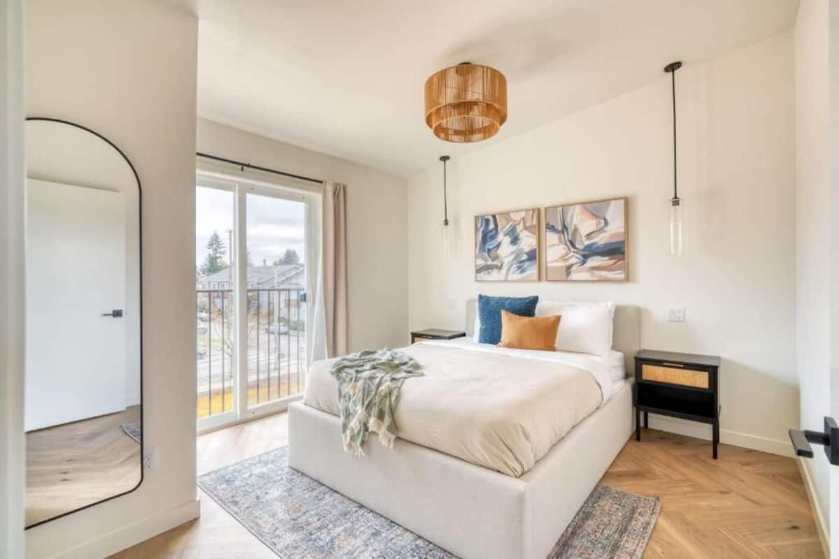 Un dormitorio con una cama grande, vistas al exterior, una lámpara de techo y un cuadro en la pared.