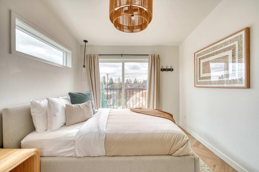 A bedroom with a bed, a window, a view, and a hanging light fixture.