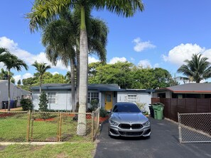 Ein Wohngebiet mit einem Haus, einem parkenden Auto und einem umzäunten Garten.