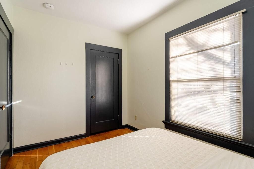 Une chambre à coucher avec un lit, une porte et une fenêtre équipée de stores.