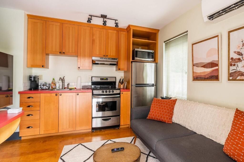 A compact living space with wooden cabinets, a kitchenette, a sofa, and artwork on the walls.