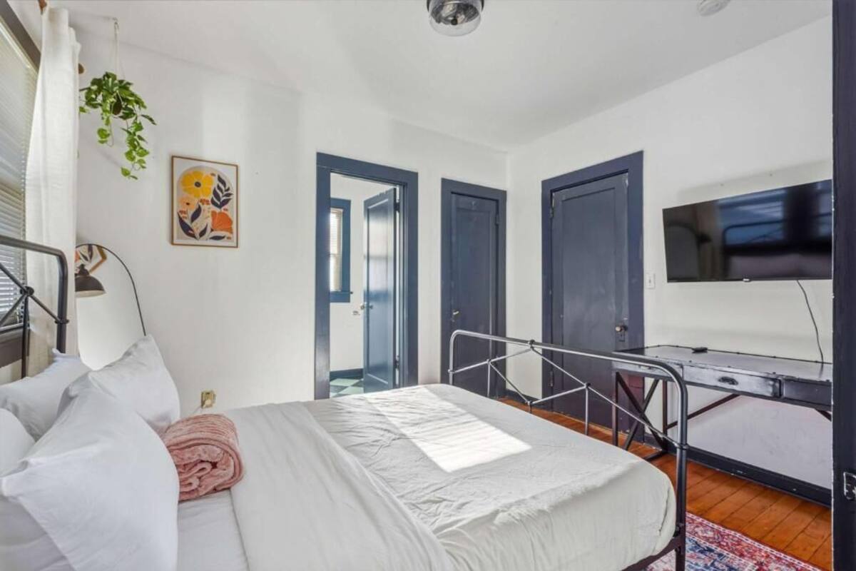 Un dormitorio con cama, escritorio, televisor y puerta.