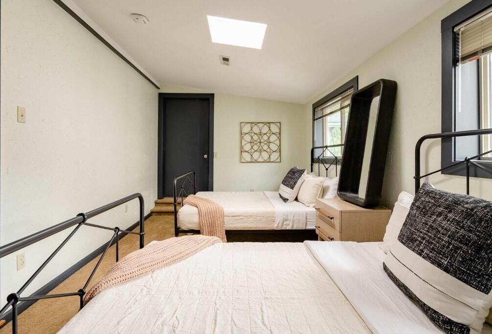 Un dormitorio con dos camas, una ventana, una puerta y una lámpara en el techo.